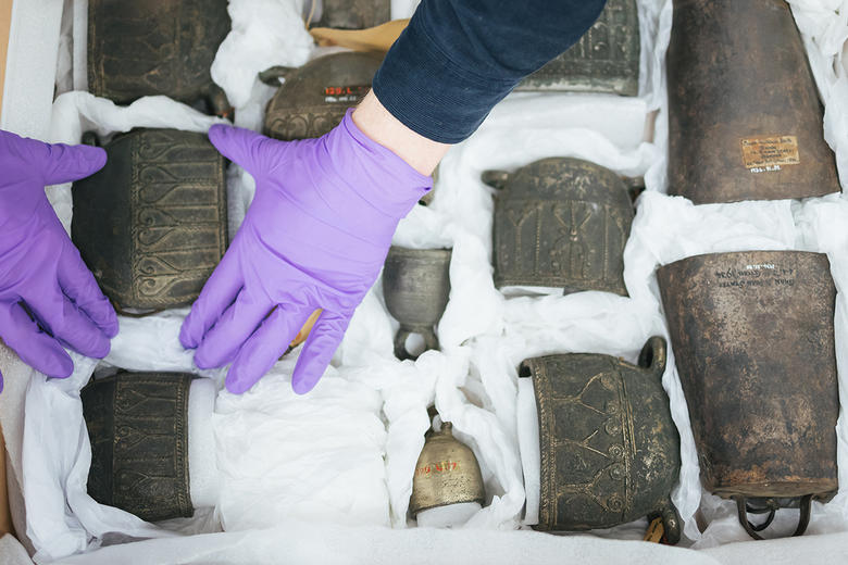 Gloved hands packing a collection of bells