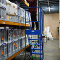 woman putting box on shelf via ladder