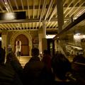 Silhouettes of backs of guests' heads as they watch a speaker at the museum entrance