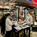 three adults gather round a table with handling objects and photographs on it.