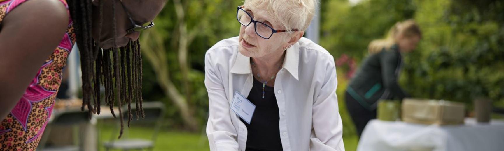 Volunteer at the Botanic Garden showing visitor some activities on an activity station