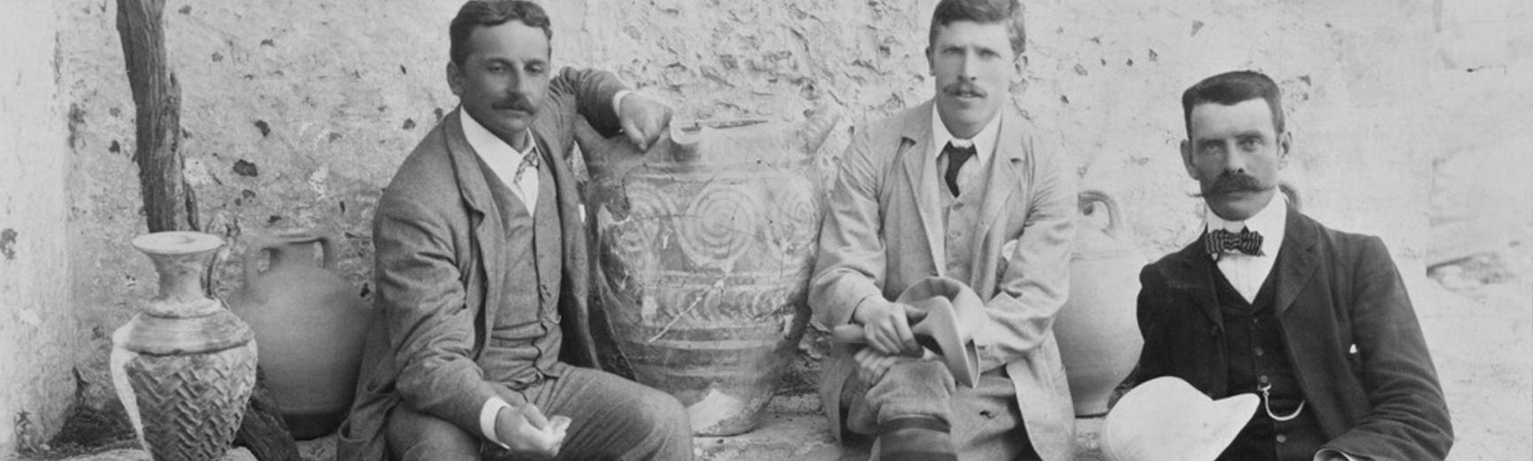 Black & white photograph of three men with ancient pottery
