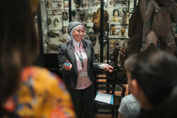 multaka oxford volunteer providing a tour to visitors in front of a case  at the pitt rivers museum