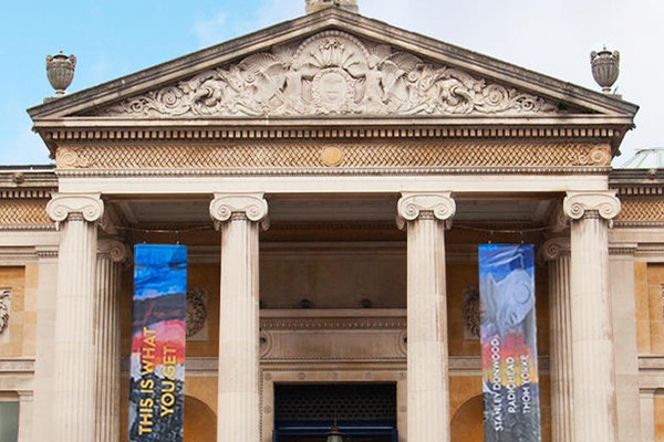 The Ashmolean's stone entrance facade, featuring central glass doors framed by pillars.