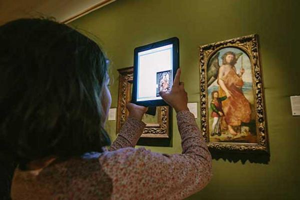 Young person examining art work using iPad application in the Ashmolean Museum