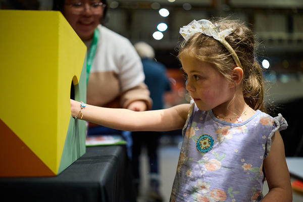 A young girl examines a red, yellow and green box.