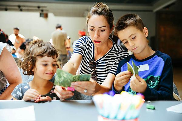 An adult and two children engage in arts and crafts activities.