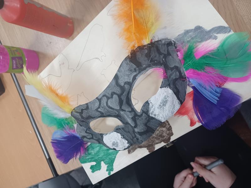 A painted eye mask with feathers; children's craft