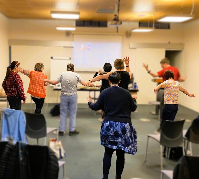 Dance around the world A group of adults from behind dancing in a conference room.