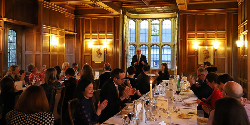 Adults clapping while sitting at long dinner tables