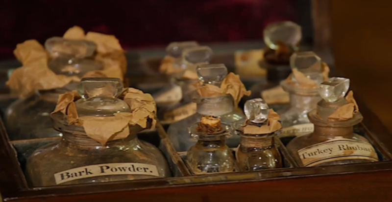 An antique medicine chest filled with old bottles filled with medicinal powders