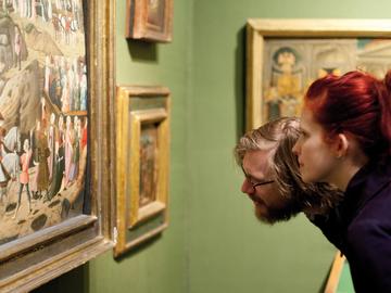 man and woman looking closely at Ashmolean painting