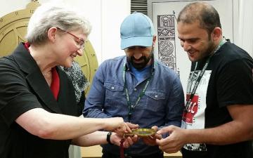 Three adults examine an astrolabe