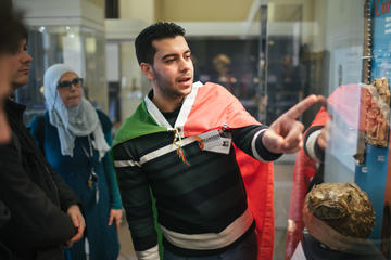 Volunteer Hussein Kara Ahmed leading a tour at the History of Science Museum Volunteer Hussein Kara Ahmed leading a tour, standing by a case of objects, at the History of Science Museum