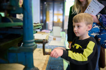 Young boy in front of printing press at HSM 100 public event 