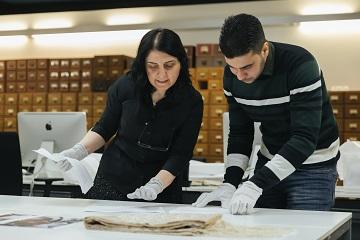 volunteers look at a scarf from damascus