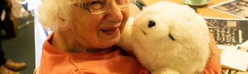 Smiling woman with therapeutic robot seal