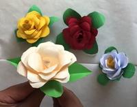Photograph of 4 paper flowers, each a different colour, with 4 paper leaves coming out from the underside of each flower.