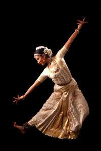 Music and Dance image. Photograph of a young Indian woman in a dance pose, wearing cream coloured traditional Indian dress and head accessories.