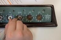 a hand turning dials on a radio system function panel.