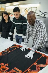 Volunteers nav hussein and niran lay out a dress from saraqib in syria credit ian wallman resized Volunteers Nav, Hussein and Niran lay out a dress from Saraqib