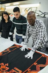 Volunteers Nav, Hussein and Niran lay out a garment