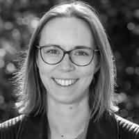 Black and white headshot of staff member Cathy King, who wears glasses and has shoulder-length hair. 