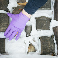 Gloved hands packing a collection of bells